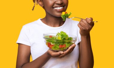 Taze salata yiyen Afrikalı bir kadın.