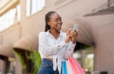 Düzenli müşteriler için özel bir teklif. Gülen Afrikalı Amerikalı kadın telefonla mesaj aldı.