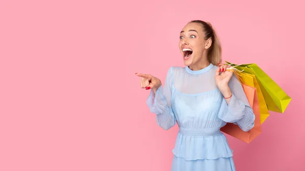 Junge Frau spaziert mit Taschen im rosa Studio — Stockfoto