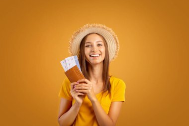 Yazlık şapkalı neşeli kadın elinde pasaport ve biletlerle