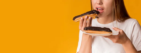 Çikolata kremalı lezzetli ekler yiyen tanınmamış genç bir kadın. — Stok fotoğraf