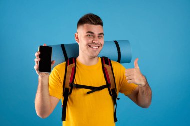 Akıllı telefonu boş ekranda gösteren ve mavi arka planda baş parmak gösteren olumlu bir adam. Web sitesi tasarımı için model