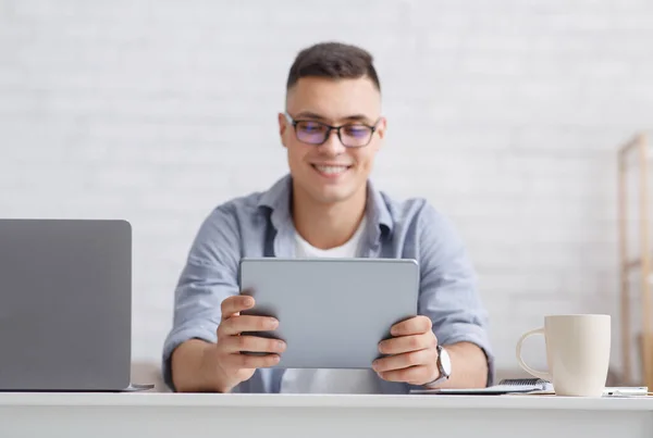 Mann schaut auf Webkamera, die Videokonferenz macht. Lächelnder Lehrer hält digitales Tablet in der Hand, sitzt mit Laptop am Tisch im Wohnzimmer — Stockfoto