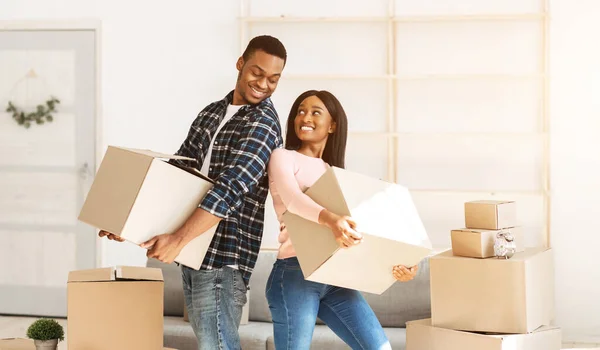 Conceito de mudança de casa. Casal preto positivo carregando caixas de papelão em sua nova casa, espaço de cópia — Fotografia de Stock