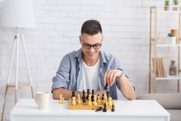 Blog video recording, chess online and free time at home during quarantine. Young man with glasses plays a board game
