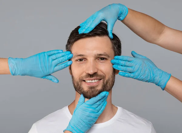 Handen in beschermende handschoenen die het gezicht van een glimlachende man raken — Stockfoto