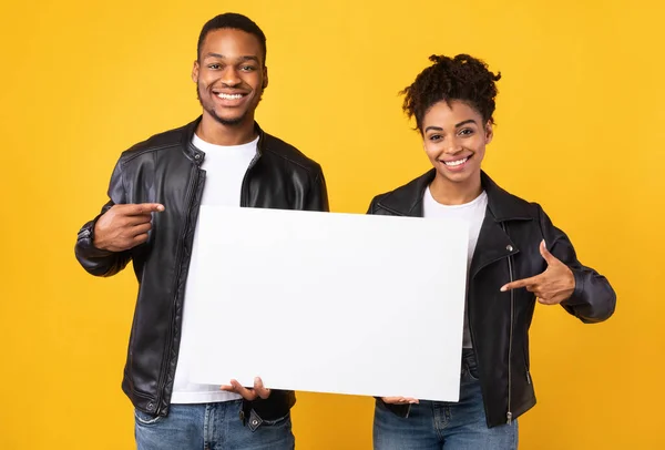 African Couple Showing Poster Pointing Fingers At Copyspace, Yellow Background — Stock Photo, Image