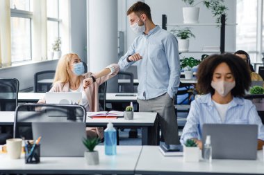 Yeni normal ve birlikte çalışıyoruz. Dostça gülümseyen milenyum meslektaşları sosyal mesafeyi koruyorlar, birbirlerini selamlıyorlar, koronavirüs enfeksiyonunun yayılmasını önlüyorlar.