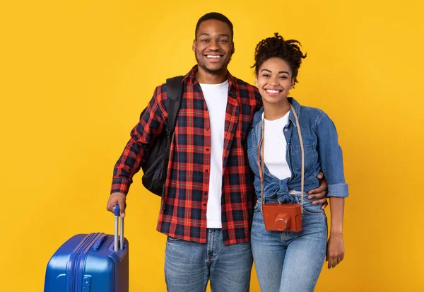 Heureux voyageurs noirs avec valise debout sur fond jaune — Photo