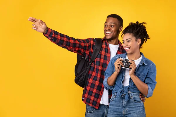 Couple africain avec appareil photo prenant des photos sur fond jaune — Photo
