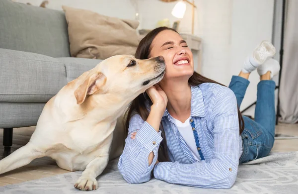 Ung leende kvinna med hund liggande på golvet — Stockfoto