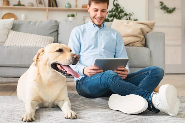 Hombre en casa con tablet digital y labrador — Foto de Stock