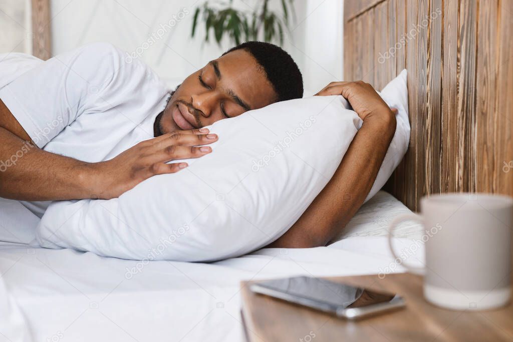 African Guy Sleeping Through Alarm-Clock Lying In Bed At Home