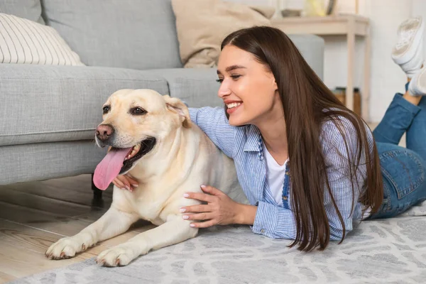 Joven dama feliz con su mascota acostada en el suelo — Foto de Stock