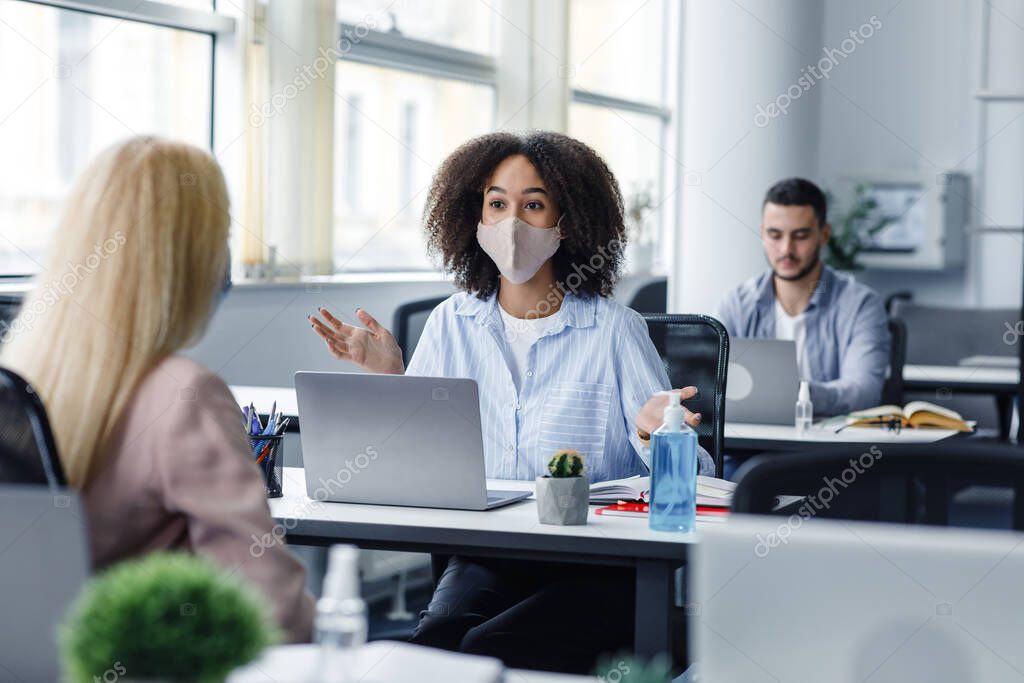 Social distance and communication with client in office during COVID-19 epidemic. African american manager advises woman and gestures at work place