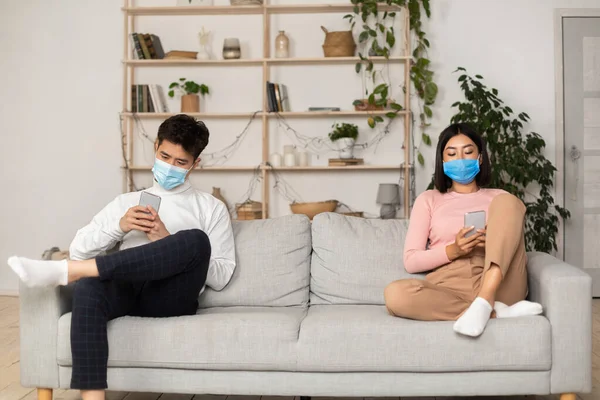 Asian Spouses In Medical Masks Texting Using Smartphones At Home — Stock Photo, Image