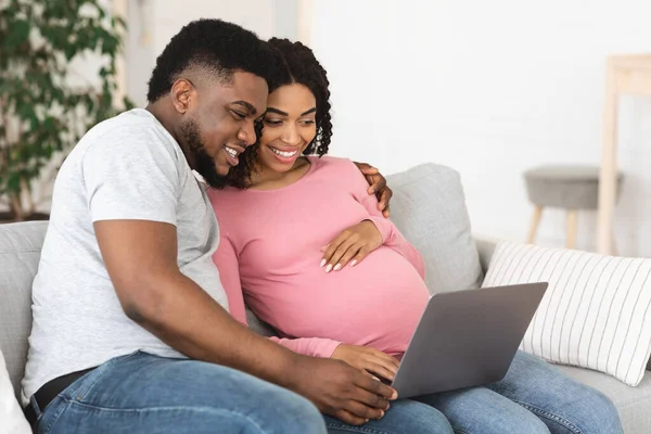 Glückliche Afroamerikanerin erwartet Familie mit Laptop im Wohnzimmer — Stockfoto