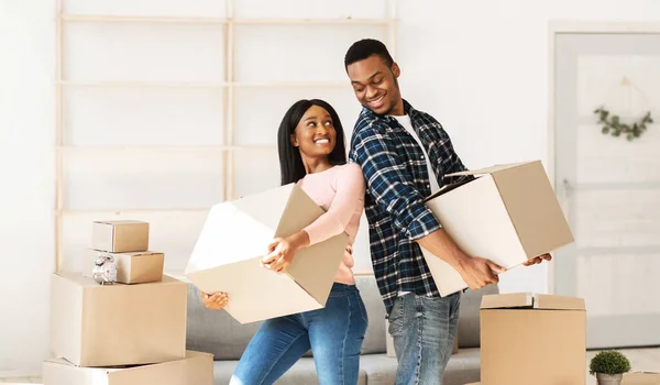 Sorrindo mulher afro-americana e seu namorado segurando caixas de papelão com seus pertences no dia da realocação — Fotografia de Stock