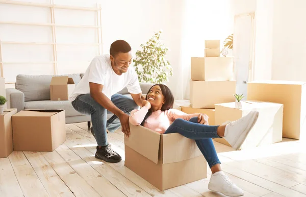 Zwarte vrouw en haar vriend spelen samen met kartonnen doos tijdens de verhuizing — Stockfoto