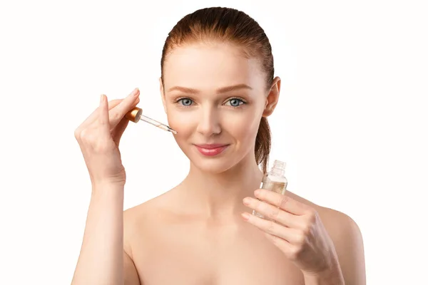 Redhaired Woman Tillämpa kosmetisk olja på ansiktet Posing In Studio — Stockfoto