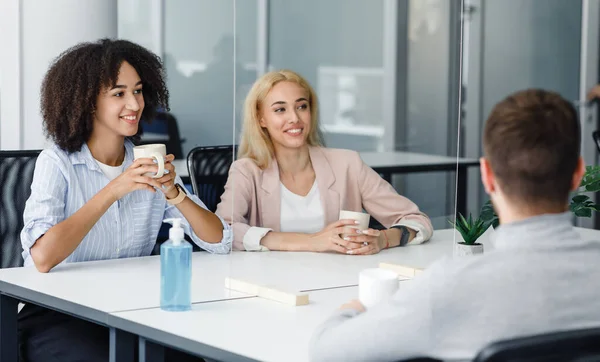 Mujeres de negocios europeas y afroamericanas sonrientes con copas que se comunican con el chico a través de la partición de vidrio —  Fotos de Stock