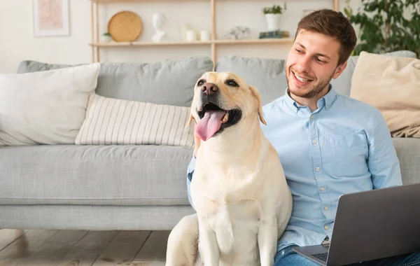 Hombre joven en casa con portátil y mascota feliz — Foto de Stock