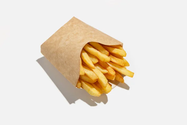 Вкусная картошка фри и нездоровый фаст-фуд в меню во время эпидемии ковид-19. Картофель в упаковке из экологической бумаги — стоковое фото