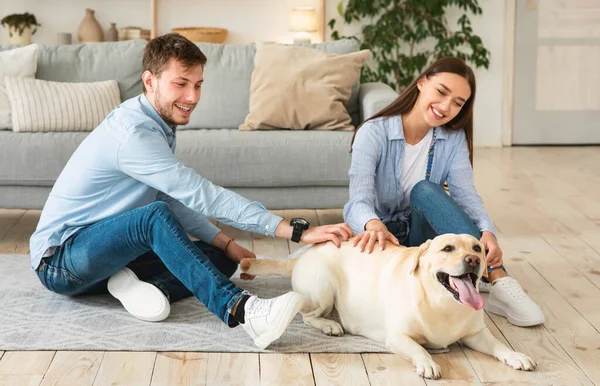 Família jovem de duas pessoas sentadas no chão com cão — Fotografia de Stock