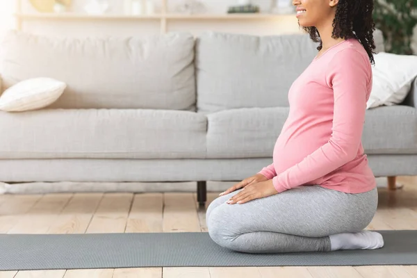 怀孕的黑人妇女坐在垫子上，在运动前做好准备 — 图库照片