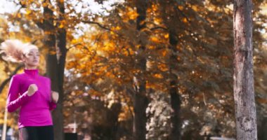 Genç koşucu, spor bilgilerini dışarıda çalışırken kontrol ediyor ve koşmaya devam ediyor.