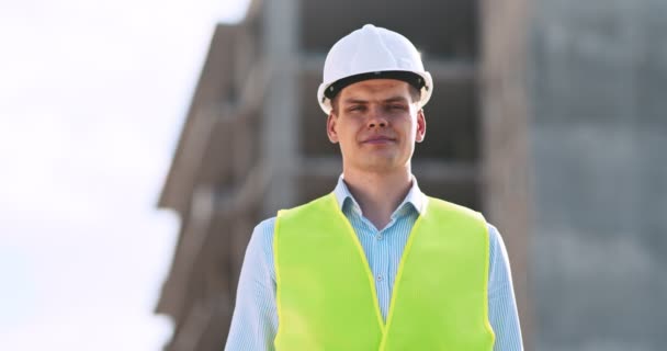 Foreman védősisakban és mellényben, hüvelykujjával felfelé az építkezésen. — Stock videók