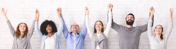 Boldog sokszínű emberek csoportja fogja egymás kezét, felemeli a karját, panoráma — Stock Fotó