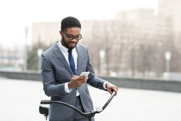 Bonito empresário mensagens de texto no telefone segurando sua bicicleta — Fotografia de Stock