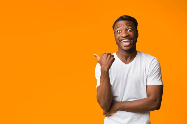 Podekscytowany Afro Man wskazujący kciuki na Copyspace Standing, Pomarańczowe tło — Zdjęcie stockowe