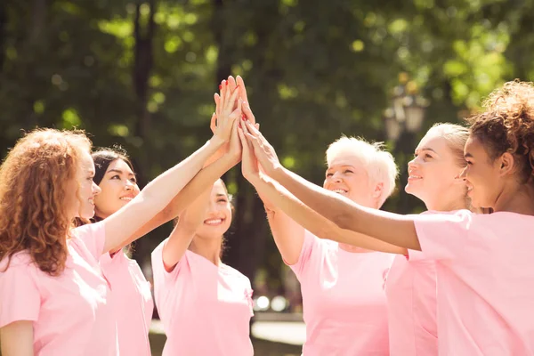 Pacjenci z rakiem piersi w różowych T-shirtach dając wysokiej piątki na świeżym powietrzu — Zdjęcie stockowe