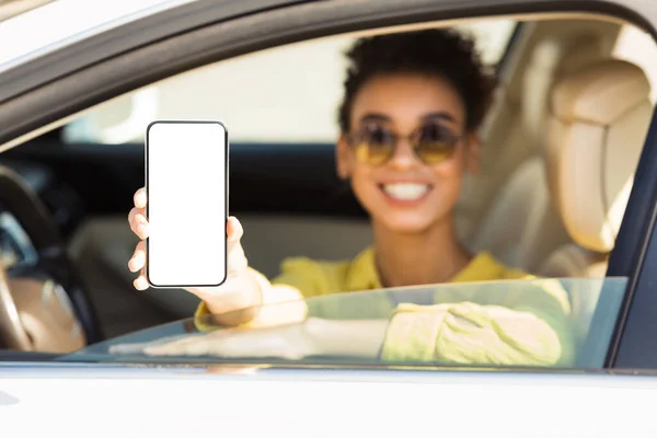 Uśmiechnięta kobieta wyświetla telefon z pustym ekranem siedzi w samochodzie — Zdjęcie stockowe