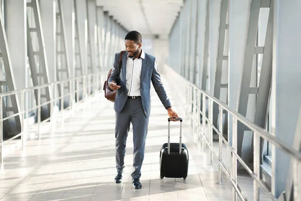 Empresario usando Smartphone caminando en el aeropuerto con la maleta interior — Foto de Stock