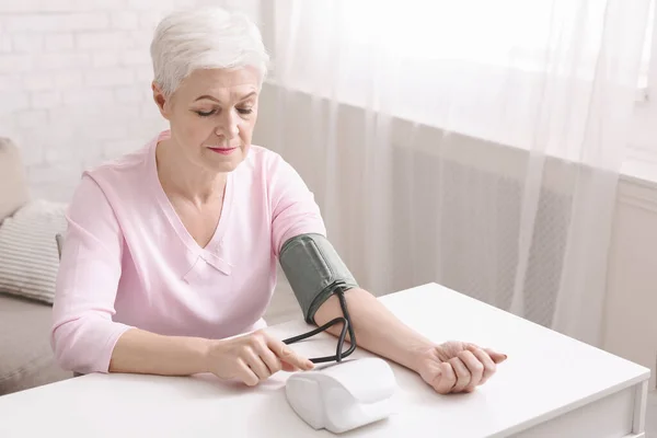 Senior lady with hypertension measuring blood pressure herself — Stock Photo, Image