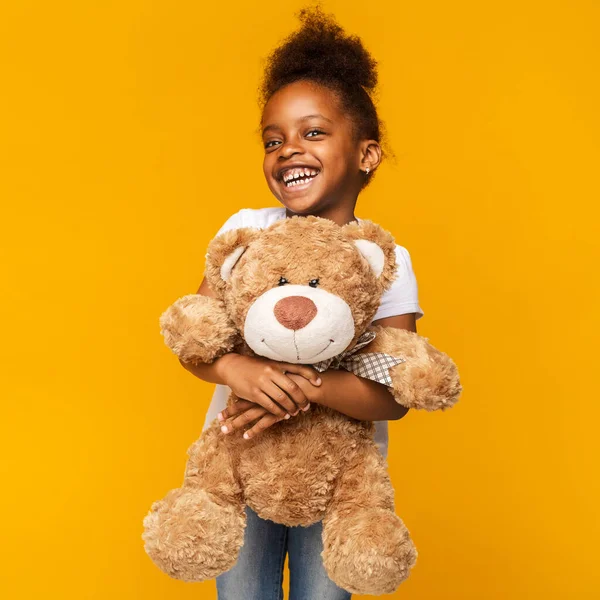 Cute black girl embracing big toy teddy bear — Stock Photo, Image