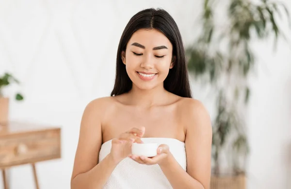 크림을 사용하여 수건으로 싸고 있는 행복 한 동양인 여자 — 스톡 사진