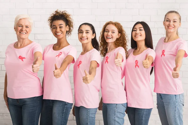 Señoras con cintas de cáncer de mama Gestos Pulgares de pie sobre la pared — Foto de Stock