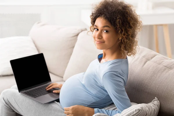 Afro-verwachtende vrouw die laptop met leeg scherm gebruikt — Stockfoto