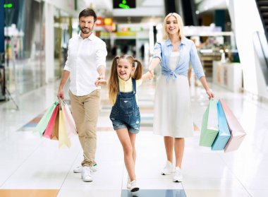Alışveriş merkezinden alışveriş yaptıktan sonra alışveriş yapan üç kişilik bir aile.