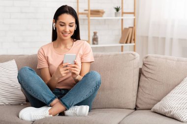 Kulaklık takan kadının portresi telefonla müzik dinlemenin keyfini çıkarıyor.