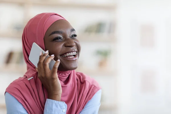 Mobil kommunikáció. Vidám fekete muszlim nő beszél mobilon, közelkép lövés — Stock Fotó