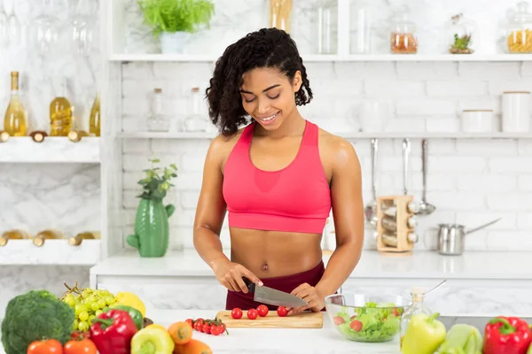 Vacker ung afro kvinna förbereder grönsakssallad hemma — Stockfoto