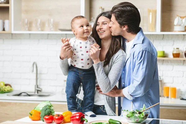 Familia joven abrazándose con el bebé en la cocina, espacio vacío — Foto de Stock