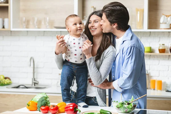 Mutfakta bebeğe sarılan genç aile, boş bir alan. — Stok fotoğraf