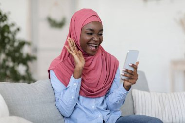 Karantina sırasında iletişim. Evde akıllı telefondan görüntülü arama yapan Müslüman Kadın