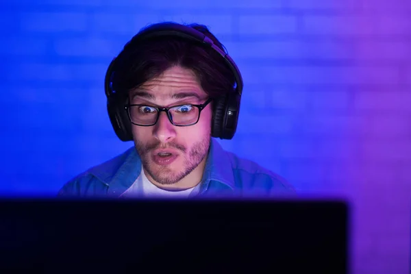 Zszokowany gracz mający problem z graniem w grę komputerową w domu, słabe oświetlenie — Zdjęcie stockowe